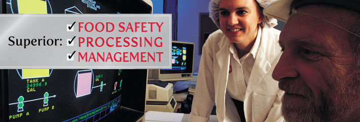 Dairy Processing image of 2 adults in food safety attire with computer screen